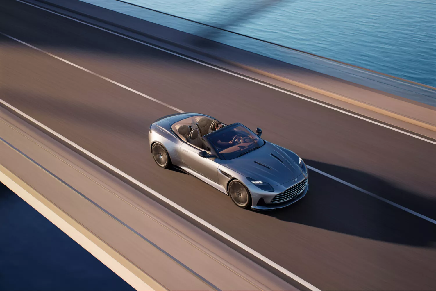 DB12 Volante crossing a coastal road with the roof down.
