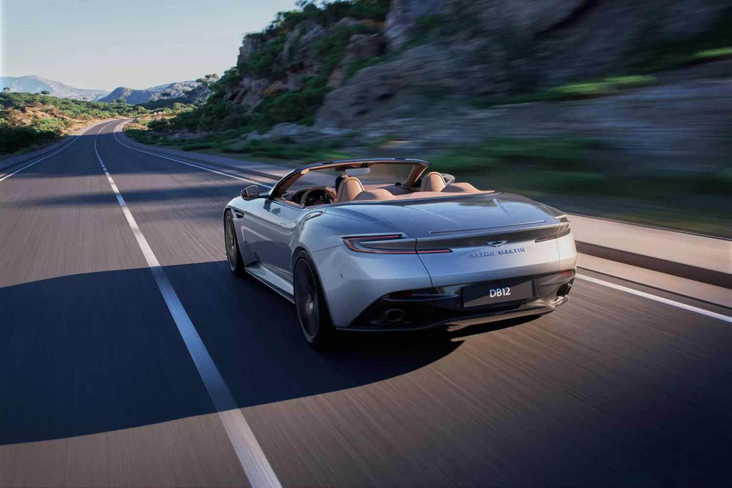 Rear three-quarter view of DB12 Volante on the open road.